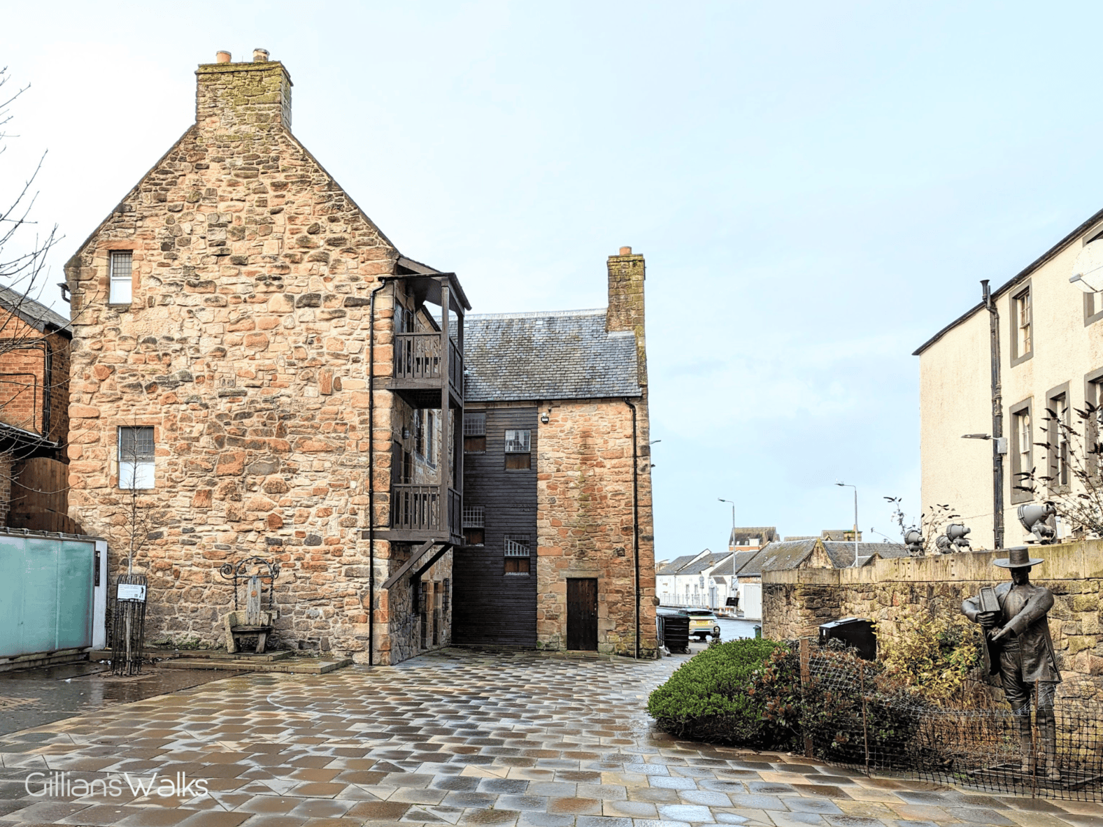 A three-storey townhouse made from stone and wood, chimneys on each end