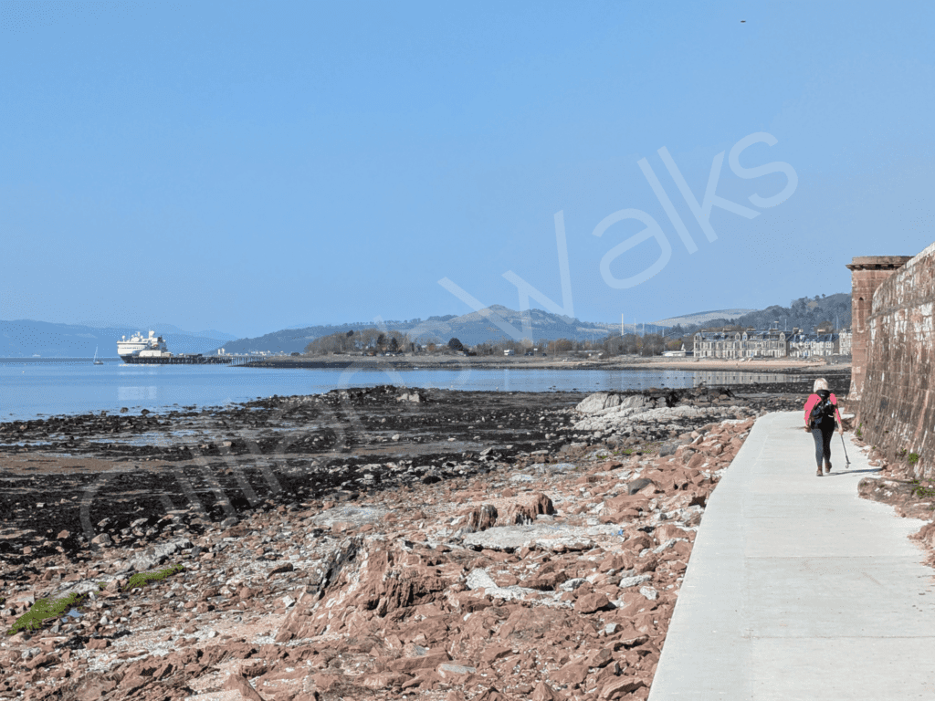 smooth concrete walkway right beside a red sandstone beach