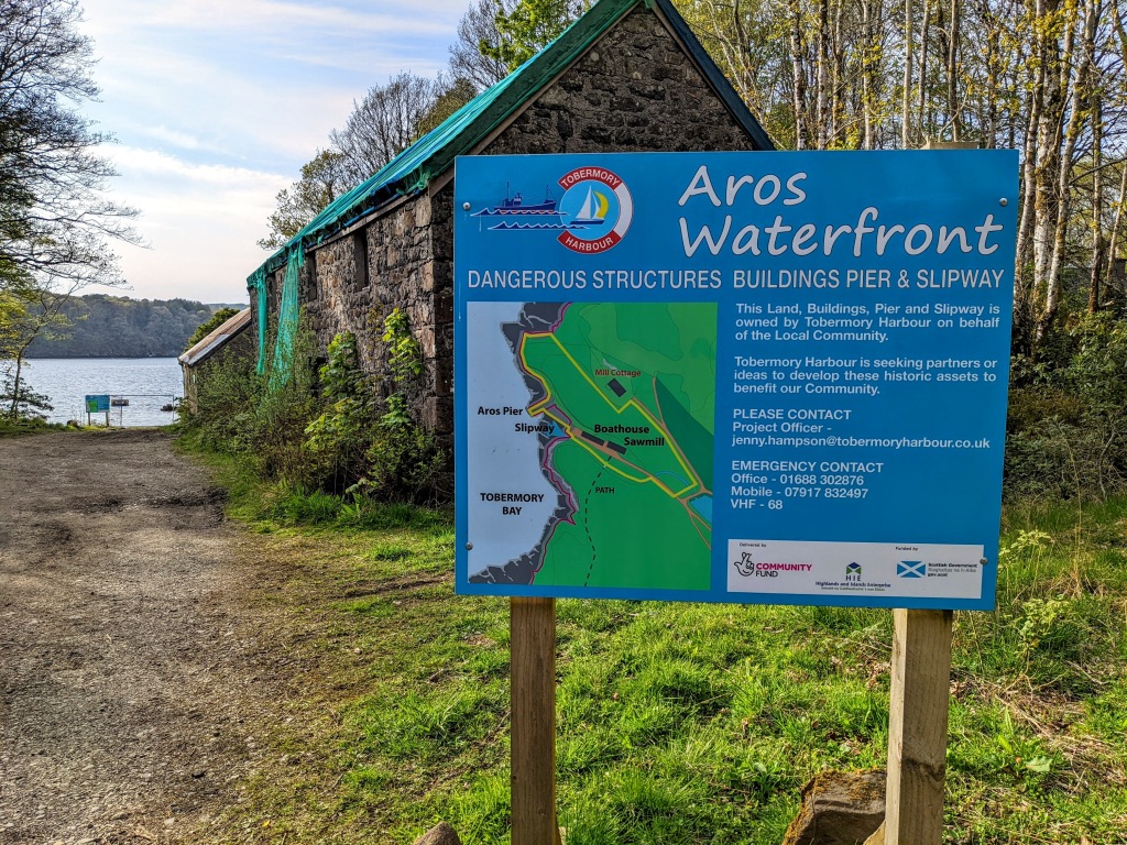 A large sign warning of dangerous structures around the pier area and information about who to contact if interested in helping to develop these historical features. 