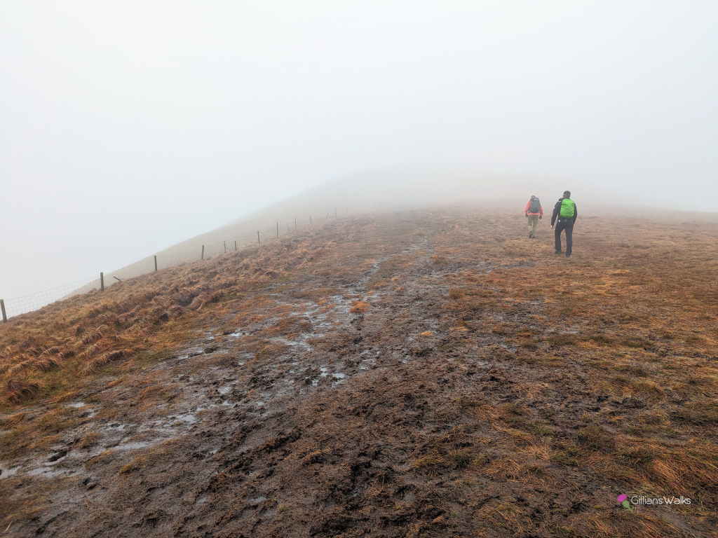 My husband and friend walking up the boggy grassy slope of Beinn Dubh surrounded by low cloud. 