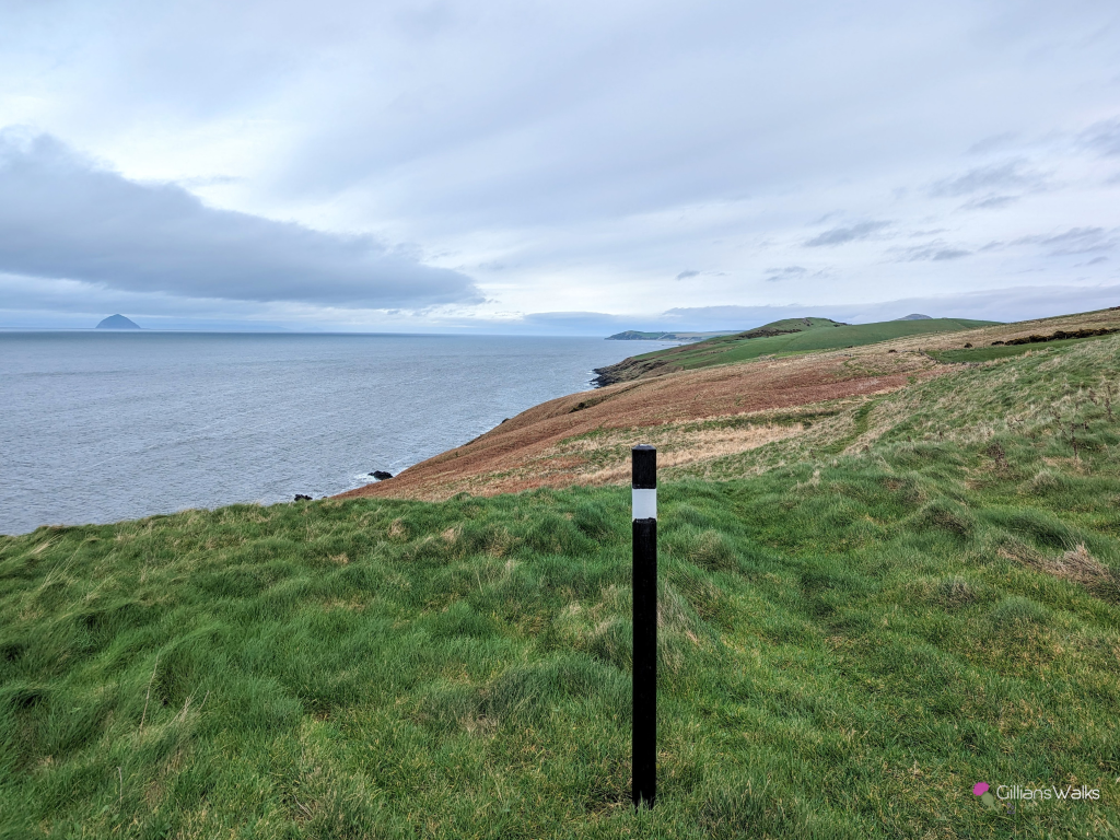 Looking north along the grassy clifftop embankment of the Ayrshire Coastal Path just north of Glenapp, one of the marker posts in the foreground. 