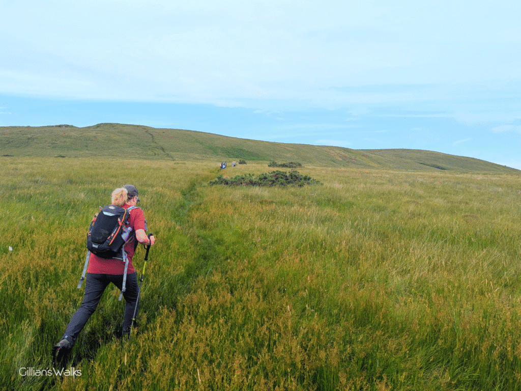 walker on an indistinct trail crossing open moorland