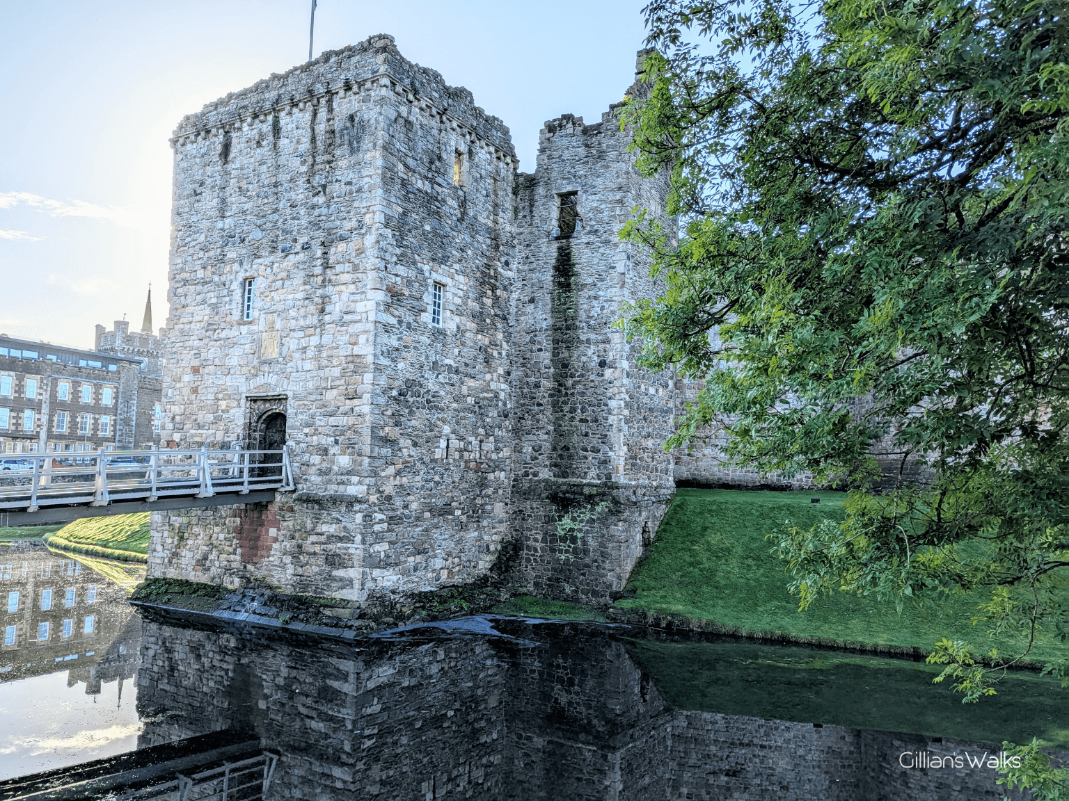 A small part of the stone walls which make up the ruins of Rothesay Castle, with water surrounding the base and a drawbridge leading across to a doorway high above ground level